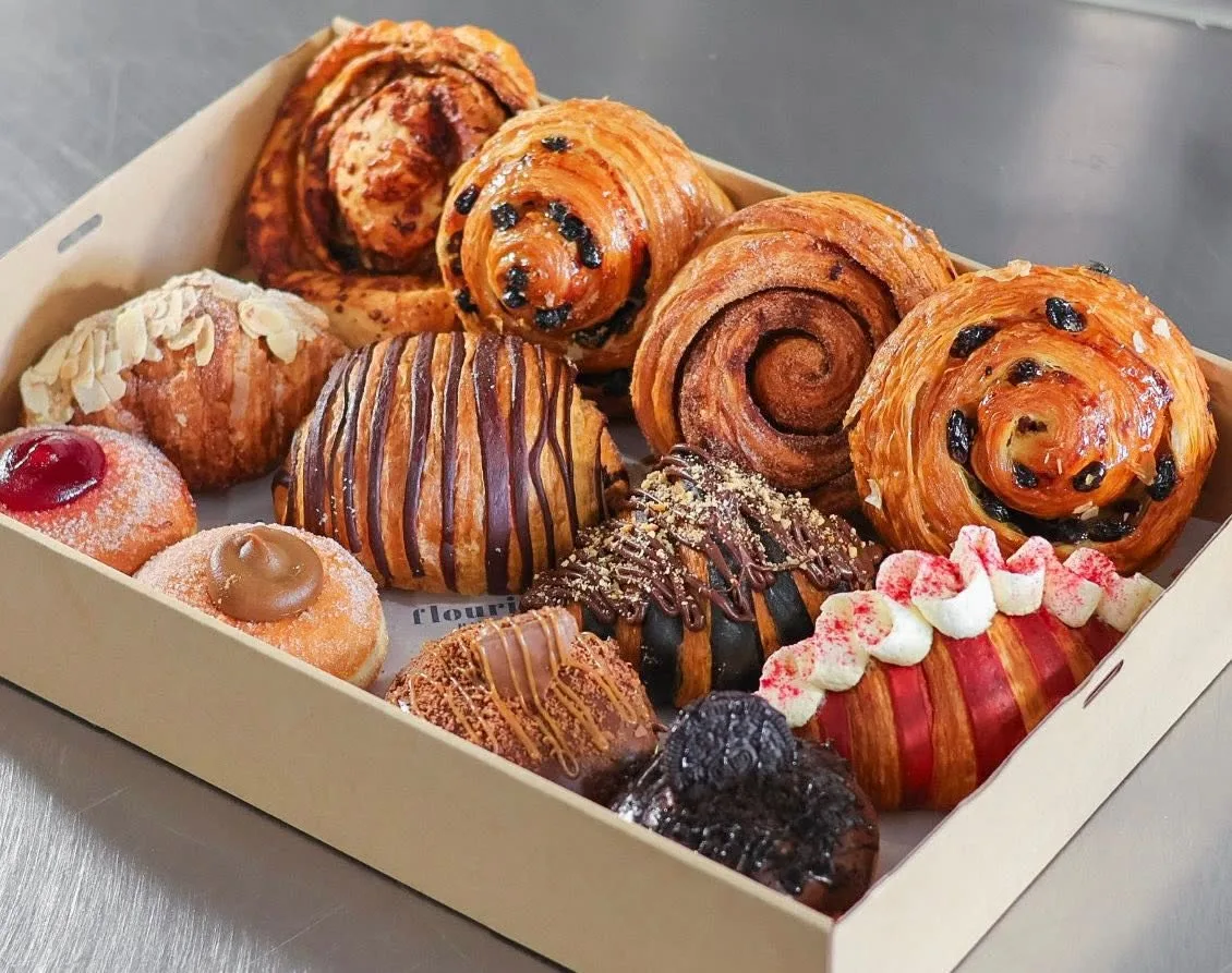 A box of pastries: cinnamon scrolls, chocolate-striped croissants and filled doughnuts