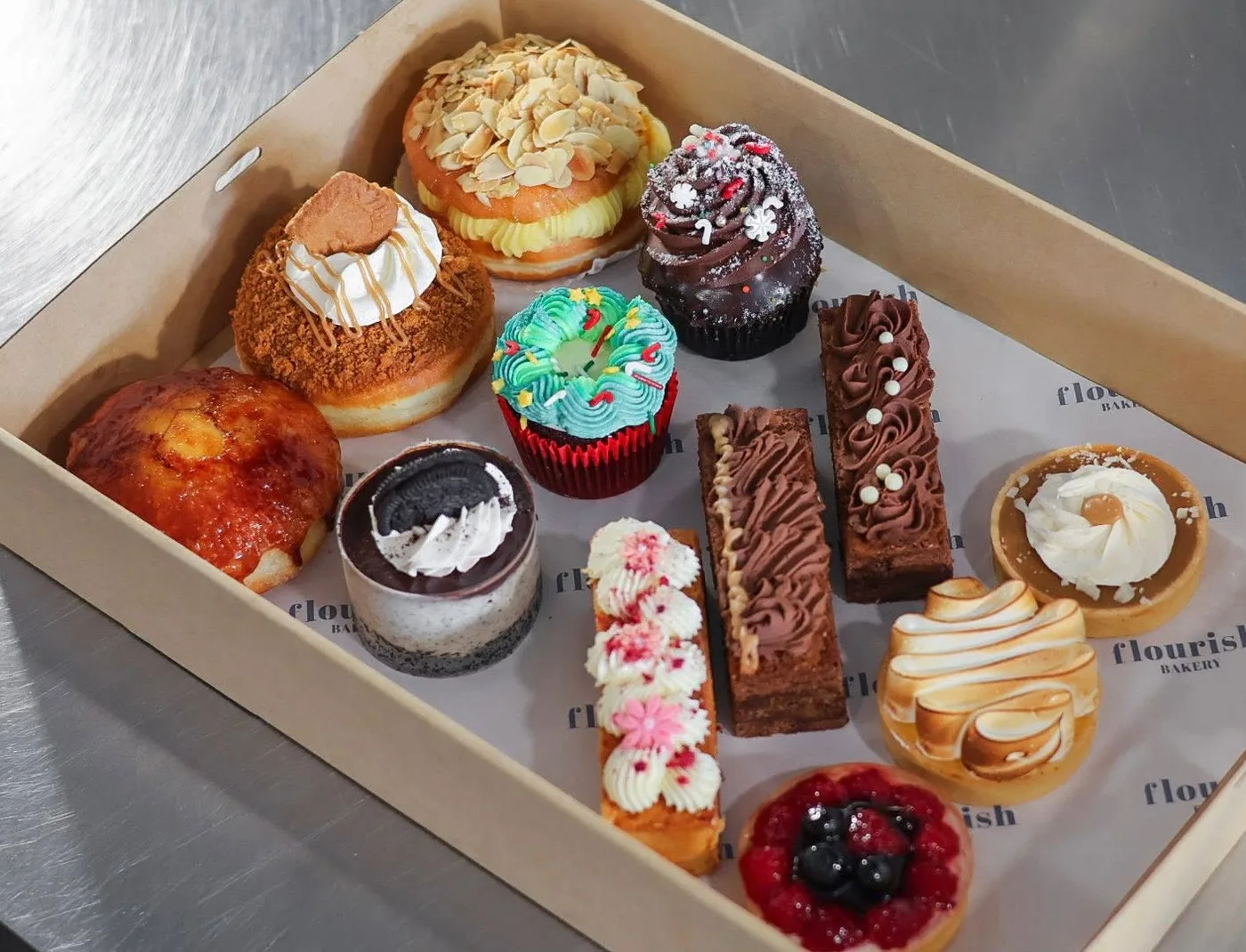 A box of sweets including cupcakes, tarts, brownie slices and a filled doughnut